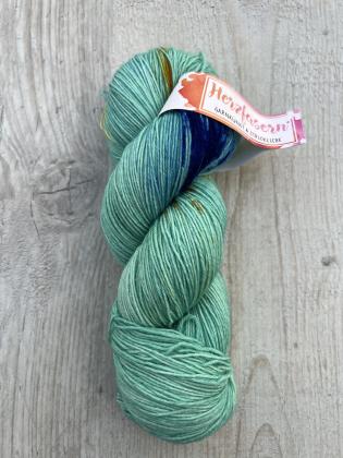 Alternativtext Bild: Strang handgefärbte Wolle in Türkis mit blauen und goldenen Sprenkeln, Herzfasern No. 20 – Aquasplash. 	•	Kontraste im Shop: Holz-Hintergrund bietet guten Kontrast. 	•	Schriftgröße: Mindestens 16px für Beschreibungstext. 	•	Struktur: